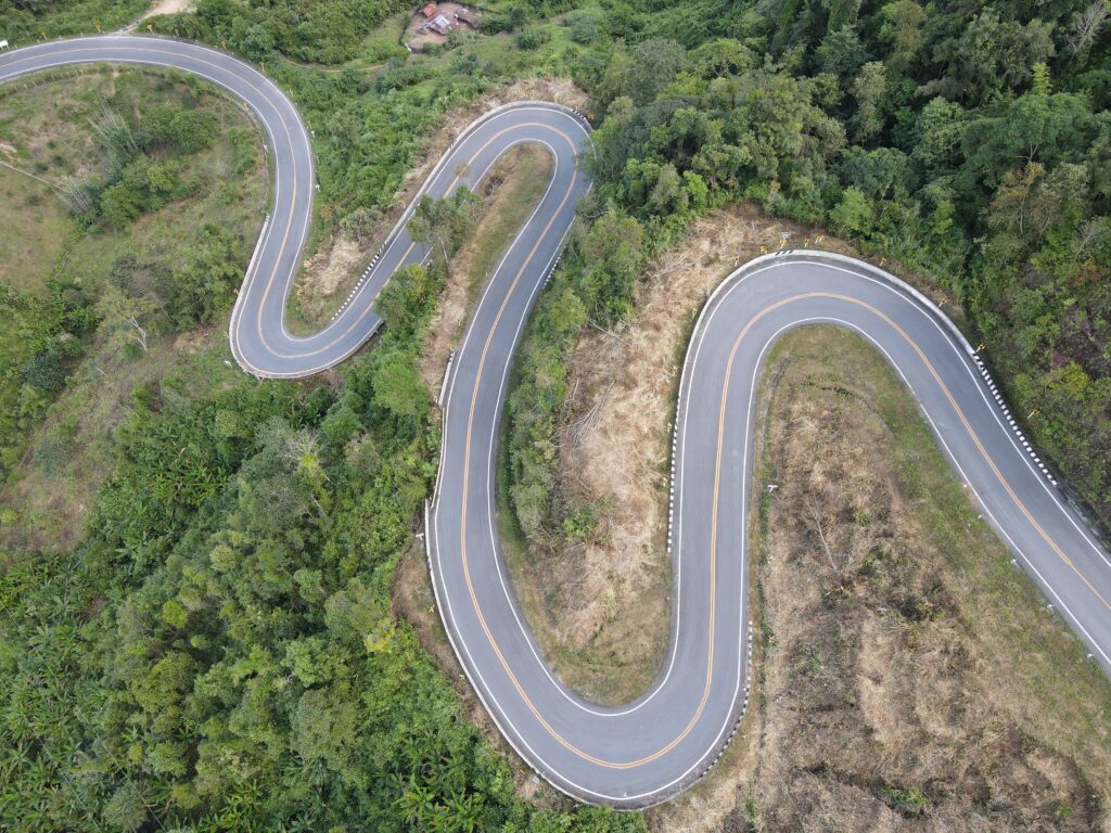 Aerial view of a winding road through lush green countryside in Bo Kluea, Thailand.